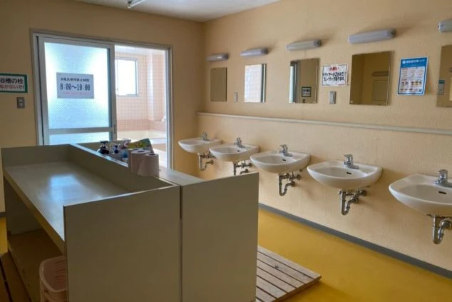 リゾートバイトの寮にある、共同浴場の脱衣所。洗面台が複数並び、広々としているので、混み合う時間でも快適に着替えができます。