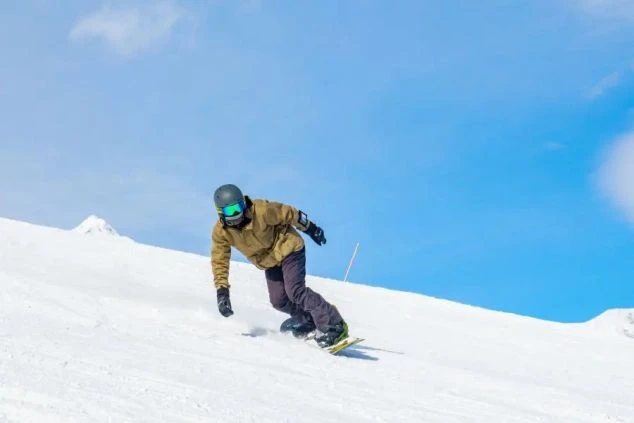 雪が舞うスキー場で、スノーボードに挑戦。リゾートバイトの休日にウィンタースポーツを楽しむ様子。