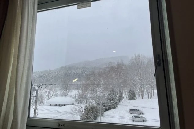 リゾートバイトの社員寮の部屋を表現するイメージ画像。窓から雪が積もった冬の風景が見える部屋。
