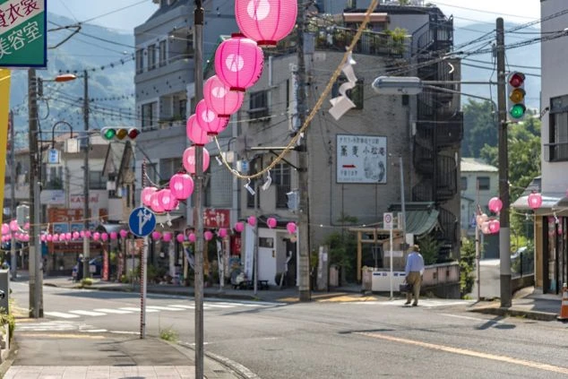 ピンク色の提灯が吊るされた、情緒あふれる湯河原温泉の商店街の街並みの画像。