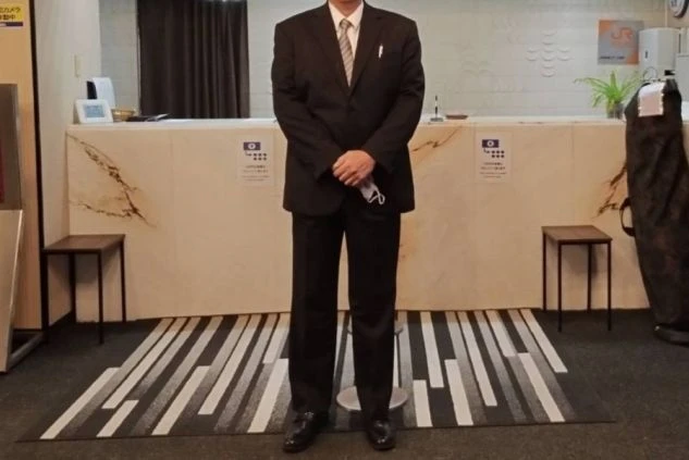 フロントスタッフの制服（スーツ）画像。落ち着いた黒のスーツにネクタイを合わせたフォーマルなスタイル。