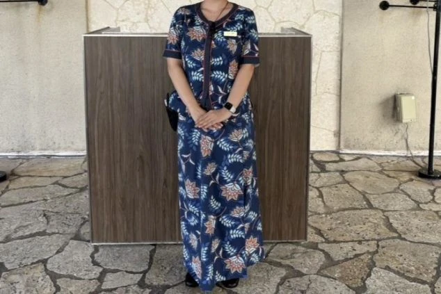 リゾートバイトの仕事風景を表現するイメージ画像。沖縄らしい花柄のワンピース風の制服を着用した女性。
