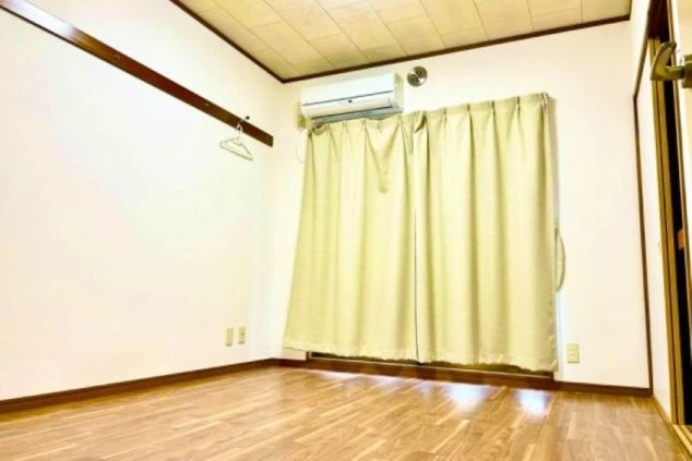 リゾートバイトの個室寮の室内。木目調の床で、エアコンが設置されている。