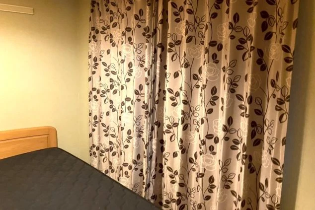 寮の居室にあるベッドと、遮光性の高いカーテン。プライバシーが守られた快適な個室寮。