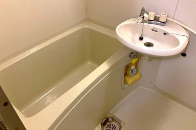 リゾートバイト寮のバスルーム。清潔感のある浴槽と洗面台が設置されているユニットバス。