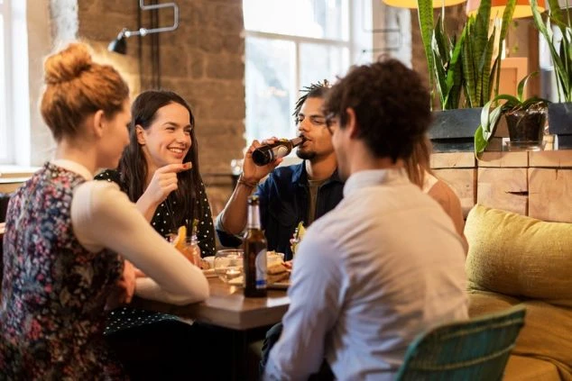 リゾートバイトの休日に、おしゃれな飲食店でビールなどを飲みながら交流する男女グループ。ワクトリの白馬エリアでの求人。