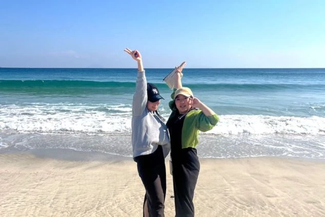 伝統的な日本の旅館またはホテルの外観。和風の庇を持つ玄関ポーチが手前にあり、建物の高層階にはガラス張りのエレベーター塔のような構造が見える。周囲には竹や常緑樹などの木々が植えられている。