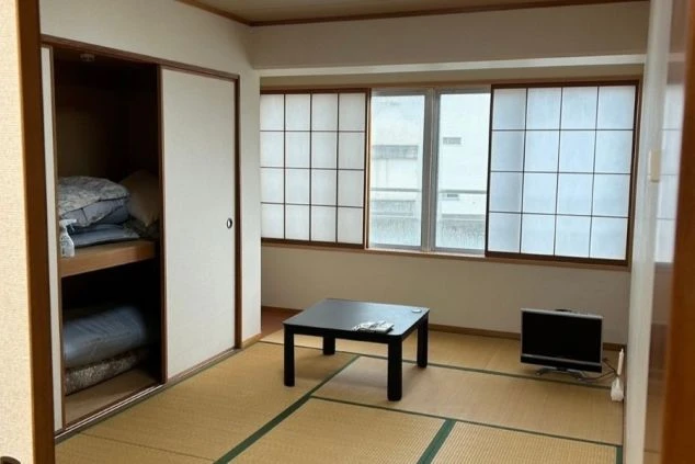 リゾートバイトの個室寮の和室。畳敷きの部屋にローテーブル、テレビ、布団が置かれた、落ち着いて過ごせる寮の部屋の画像。