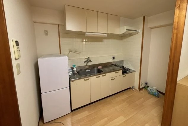 リゾートバイトの個室寮にあるミニキッチン。ガスコンロ、シンク、冷蔵庫が備え付けられ、自炊ができる便利な設備の画像。