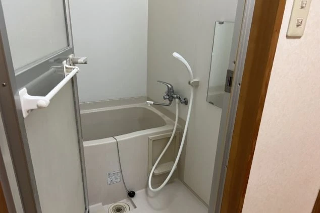 リゾートバイトの個室寮にあるバスルーム。浴槽とシャワーが一体となった、清潔感のある設備の画像。