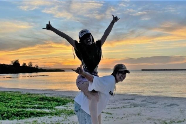 ワクトリでリゾートバイトをしているスタッフが撮影した、沖縄のビーチでおんぶする男女の画像。上に乗っている女性は両手を広げて楽しそう。