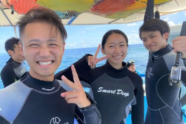 ワクトリでリゾートバイトをしているスタッフが撮影した、沖縄の海の船の上で自撮りをする男女の画像。ウェットスーツを着ている。