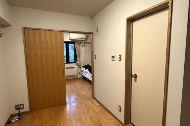 寮の玄関から居室へのアプローチ。木目調のドアやフローリングがモダンで洗練された印象を与える、セキュリティー面でも安心なスタッフ専用の居住エリア。
