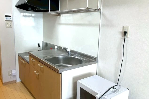 寮に備え付けのミニキッチン。調理スペース、流し台、換気扇、コンロ台、および電子レンジや冷蔵庫を置くスペース。