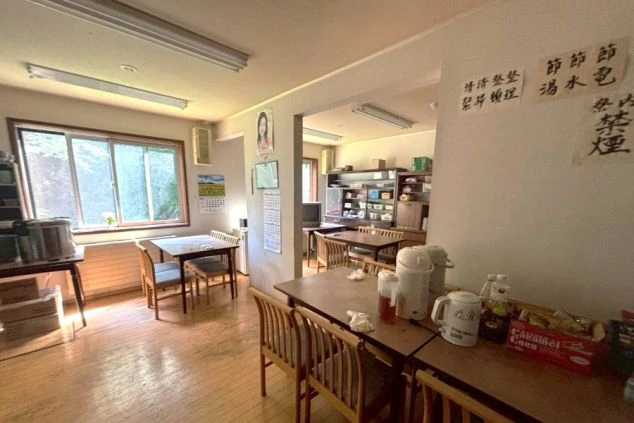 リゾートバイトの寮の共同食堂の画像。複数のテーブルと椅子が置かれており、食事や休憩に利用できる。リゾートバイトの寮の共用スペースの画像。