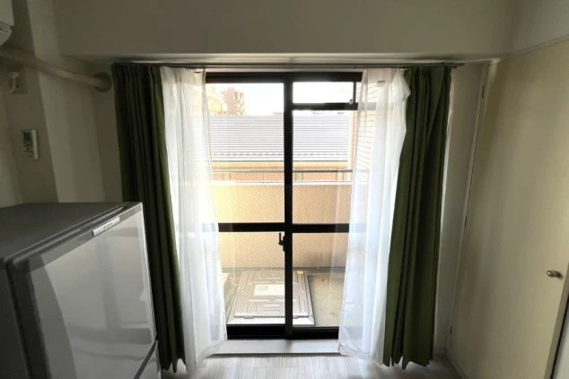 リゾートバイトの個室寮の窓の写真。明るい光が入る窓辺と、遮光カーテン。日当たりの良い快適な寮のイメージ。