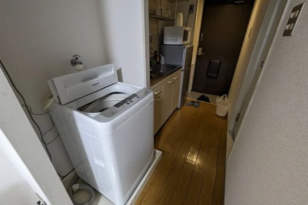 リゾートバイトの寮に設置された洗濯機とミニキッチンの写真。自炊可能で生活費を抑えられる充実した設備。