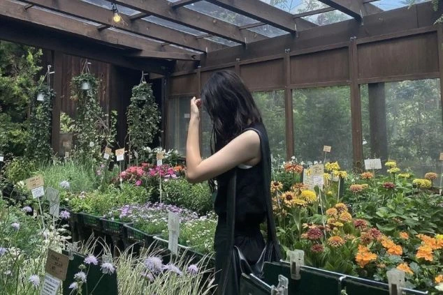 植物の間に立つ女性の画像。