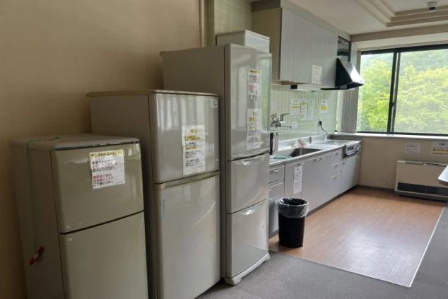 リゾートバイトの寮に備え付けられた、共用キッチンの画像。複数の冷蔵庫とシンク、コンロが並んでおり、共同で料理ができるようになっている。リゾートバイトの寮の共用キッチンの画像。
