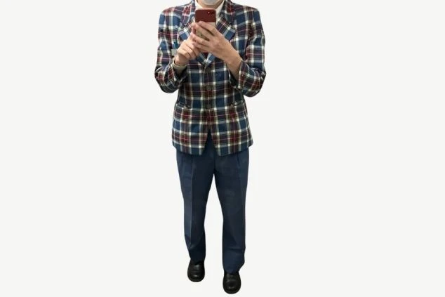 チェック柄のジャケットと、青いパンツを着用した男性スタッフの画像。赤いネクタイを着用しており、冬用の制服である。リゾートバイトの仕事内容を表す、フロントスタッフの制服の画像。