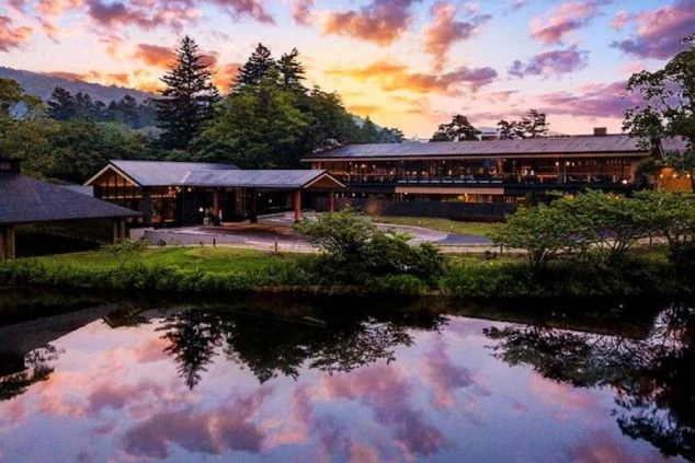 長野県軽井沢のホテルの外観の画像。水面に建物が反射している。夕暮れ時。