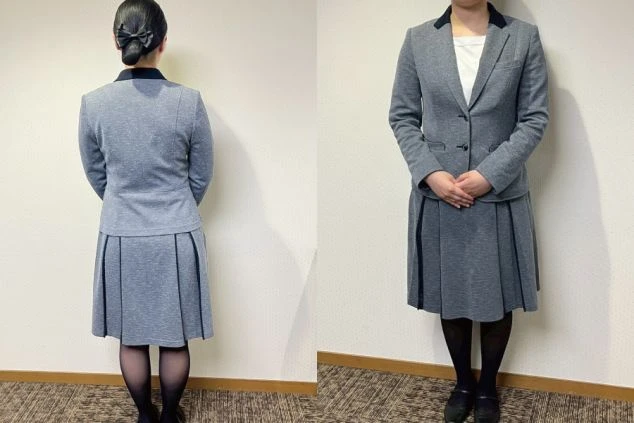 フロントスタッフの制服を着た女性。グレーのジャケットとプリーツスカートのセットアップで、黒い襟とパイピングがアクセントになっている。女性は後ろ姿と正面からの2つのポーズで写っている。