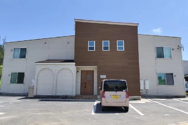 ブラウンと白のツートンカラーの外壁が特徴的な、モダンなデザインの2階建てアパートの外観。