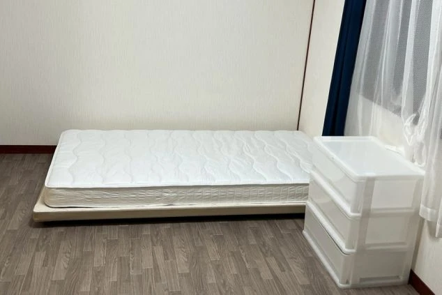 リゾートバイトスタッフが一人で使う個室のベッドルーム。広いベッドと、荷物整理に便利なプラスチック収納ケース。