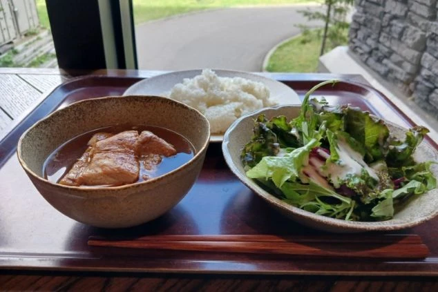 まかないを表現するイメージ画像。肉の煮込み料理とサラダ、ご飯がワンプレートになった食事。