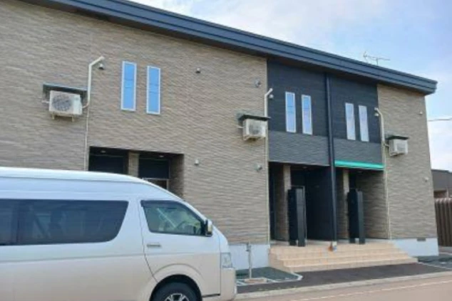 ワクトリの社員が出張で撮影した、リゾートバイトの長期寮の外観の画像。モダンなデザインの2階建てアパートメントタイプで、白いバンが手前に駐車されている。