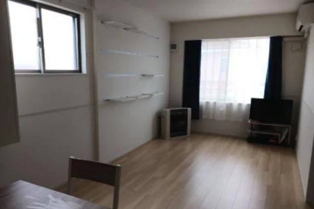 ワクトリの社員が出張で撮影した、リゾートバイトの長期寮の部屋の画像。フローリングの広々とした空間に、窓、テレビ、ストーブが備え付けられている。