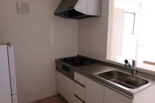 ワクトリの社員が出張で撮影した、リゾートバイトの長期寮のキッチンの画像。IHクッキングヒーターとシンクが一体になったシステムキッチンで、冷蔵庫も見える。自炊が可能な設備が整っている。