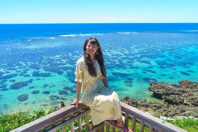 沖縄や宮古島の青い海。海岸沿いのデッキに座る女性。リゾートバイトの休日の絶景。