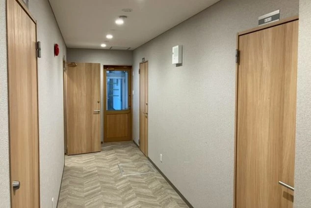 リゾートバイトの新築・築浅寮の廊下。木目調のドアとフローリングが、明るく清潔な印象です。