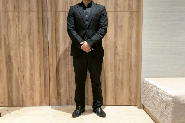 フロント(男性)制服。黒のスーツスタイルで、高級ホテルにふさわしいフォーマルで洗練された服装。