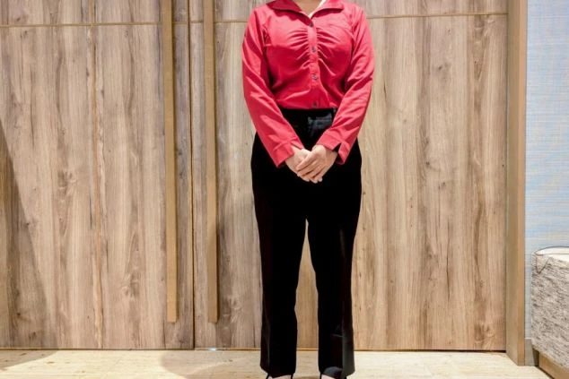 フロント(女性)制服。赤のブラウスと黒のパンツで、落ち着きの中にも華やかさがあるスタイル。