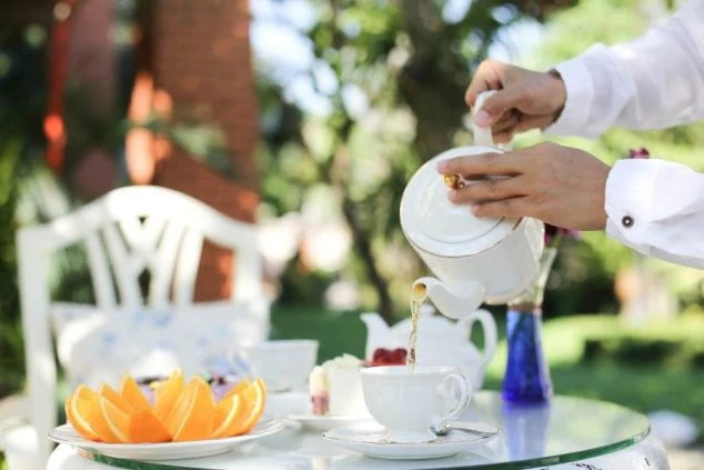 テラス席で紅茶を注ぐ様子。レストランでのリゾートバイトの仕事風景。