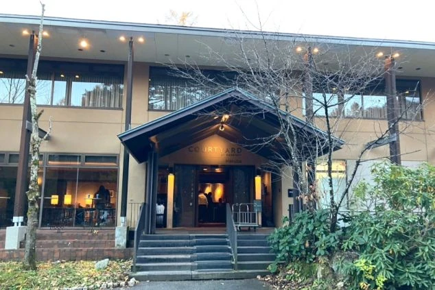 ホテルの入り口。木々に囲まれたエントランスと、屋根の下にホテルのロゴが見える。