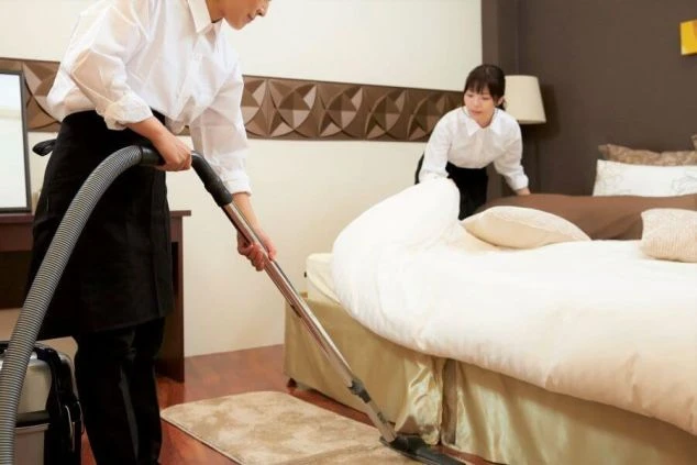 ホテル・旅館の客室清掃スタッフ。ベッドメイクや掃除機がけをするリゾートバイトの仕事風景。