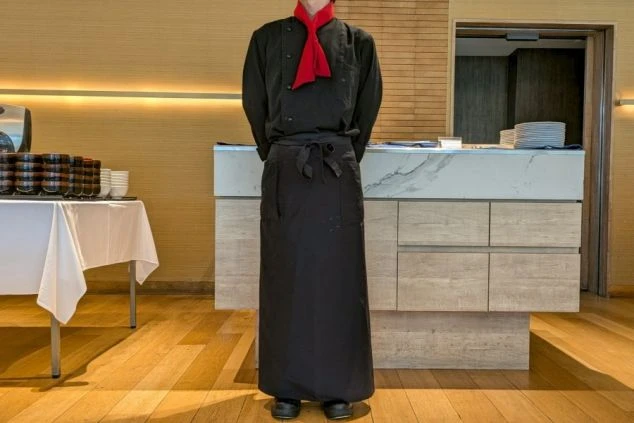 調理スタッフ制服。黒のコックコートに赤のスカーフを合わせたシックなスタイル。キッチンでのリゾートバイトの服装。