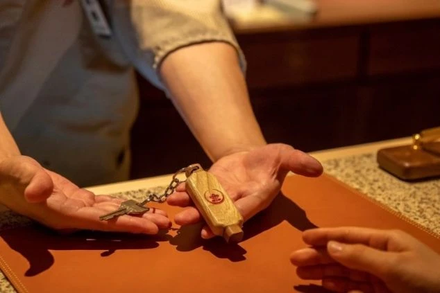 旅館の鍵をお客様に渡すスタッフ。お客様の旅の始まりをサポートする、やりがいのある仕事です。