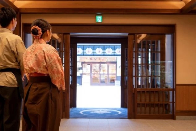 旅館の入り口に立つスタッフ。お客様を温かくお迎えし、最高の旅の思い出づくりをお手伝いできます。