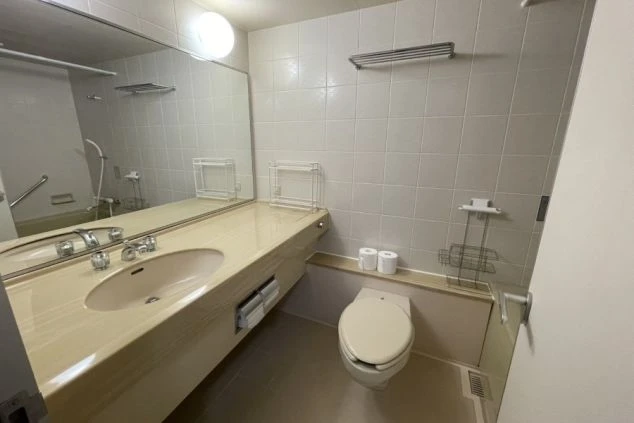 リゾートバイトの個室寮に完備された、清潔感のある洗面所とトイレ。ワイドな洗面カウンターと大きな鏡が付いたプライベートな水回り設備。