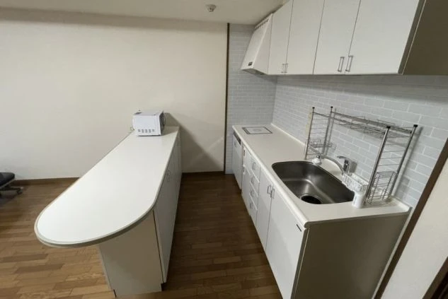 リゾートバイトで自炊可能なキッチン付き個室寮の設備。調理器具、広いシンク、電子レンジなどを備えた清潔なシステムキッチン。