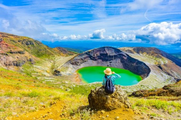 山形県蔵王エリアにある御釜に佇む人物の後ろ姿の画像。