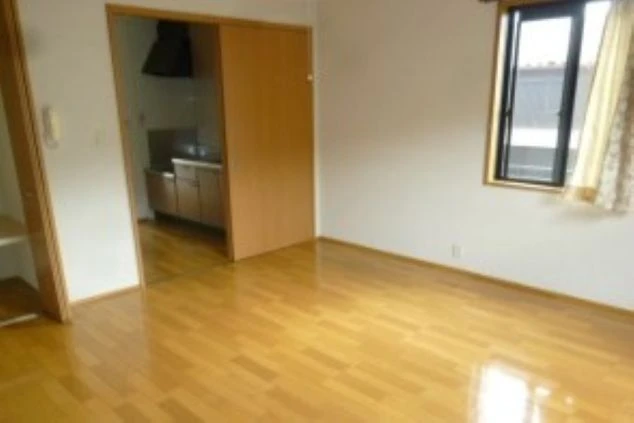 リゾートバイトの社員寮の部屋を表現するイメージ画像。茶色のフローリングの部屋と、奥にキッチンが見える間取り。