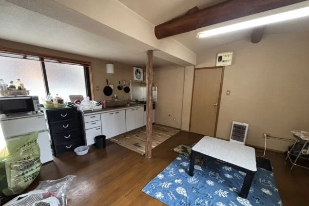 スタッフ寮の広い共用キッチンとリビングスペースの画像。電子レンジ、炊飯器、コンロ完備。