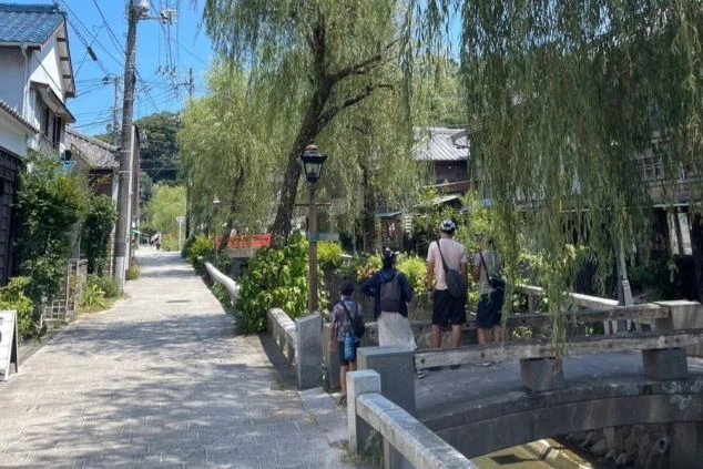 エントランスと建物外観。灰色のピラミッド型の屋根と、ベージュ色の壁、そして黒っぽい車寄せの庇（ひさし）が特徴的な建物。敷地内にはヤシの木が植えられている。