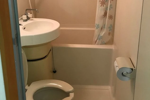 白い便器、洗面台、バスタブがまとまったコンパクトなユニットバス。花柄のシャワーカーテンが付いています。