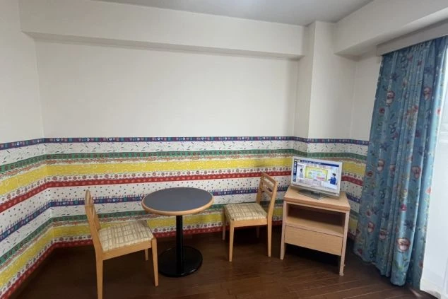 リゾートバイトの寮の個室。カラフルな壁紙が楽しい雰囲気のお部屋です。ベッドや机、収納家具などが揃っています。